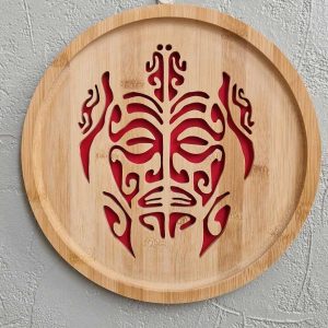 B/cadre mural rond chantourné tortue et visage maori fond rouge diamètre 26